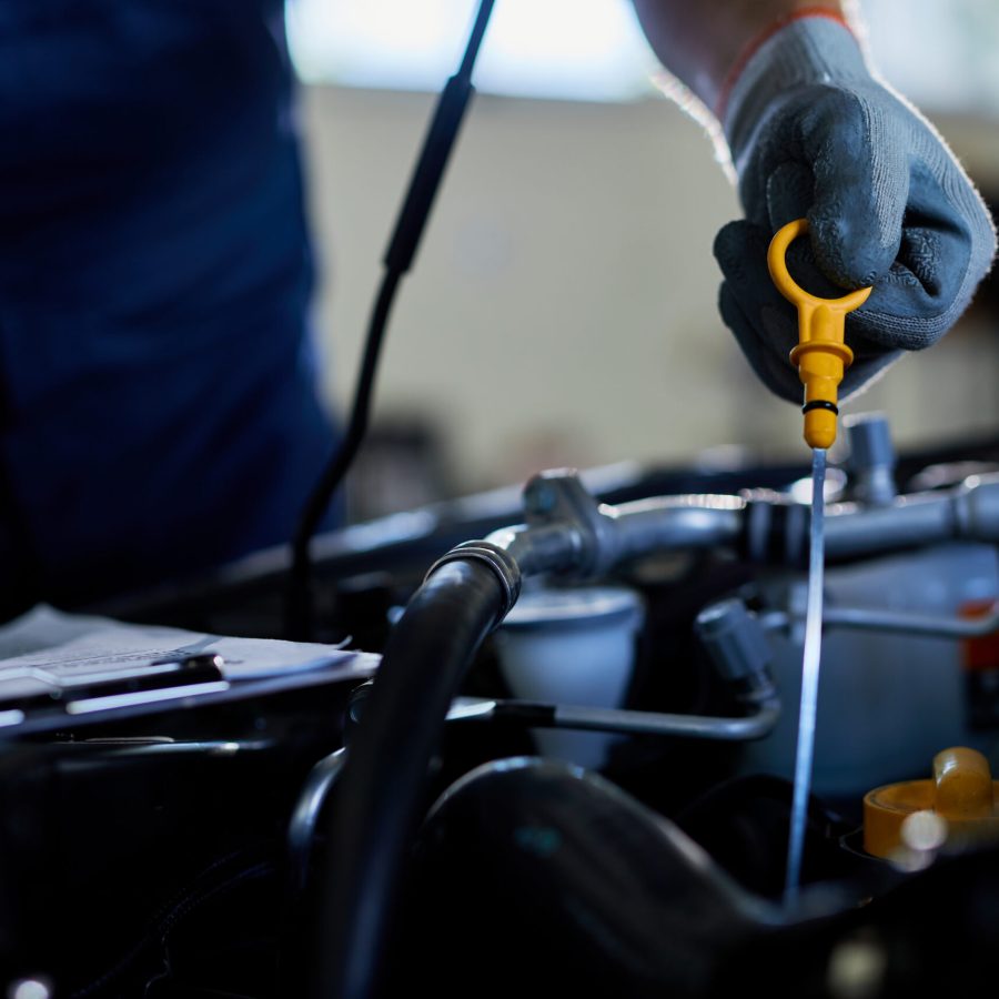 Close-up of a mechanic checking car oil in auto repair shop.